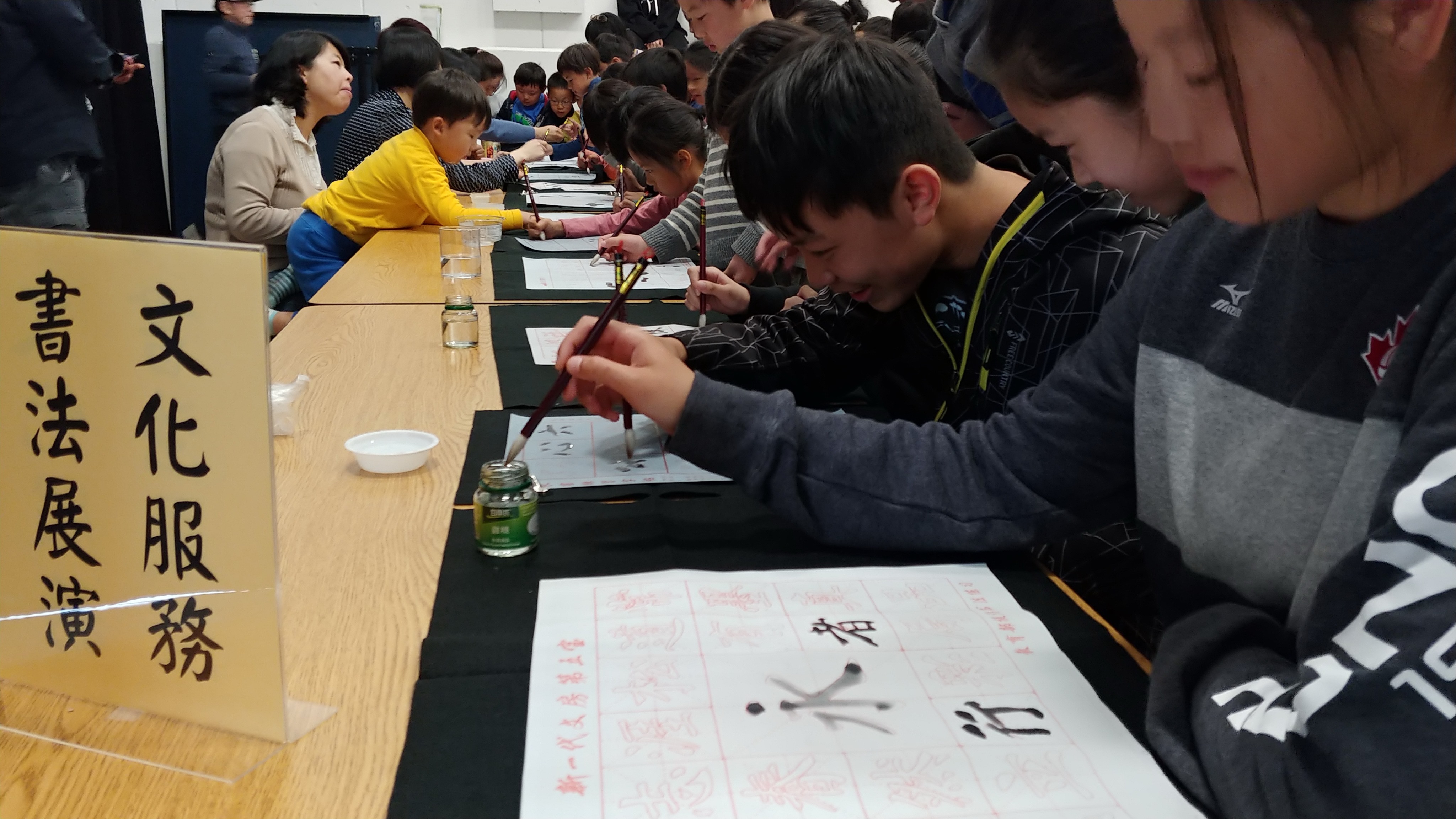 學生們聚精會神地依據水寫字帖仔細描紅書寫