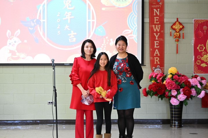洛麗中文學校校長陳翰儀（左)，家長會會長簡惠貞，和摸彩得到大金兔玩偶學生合影